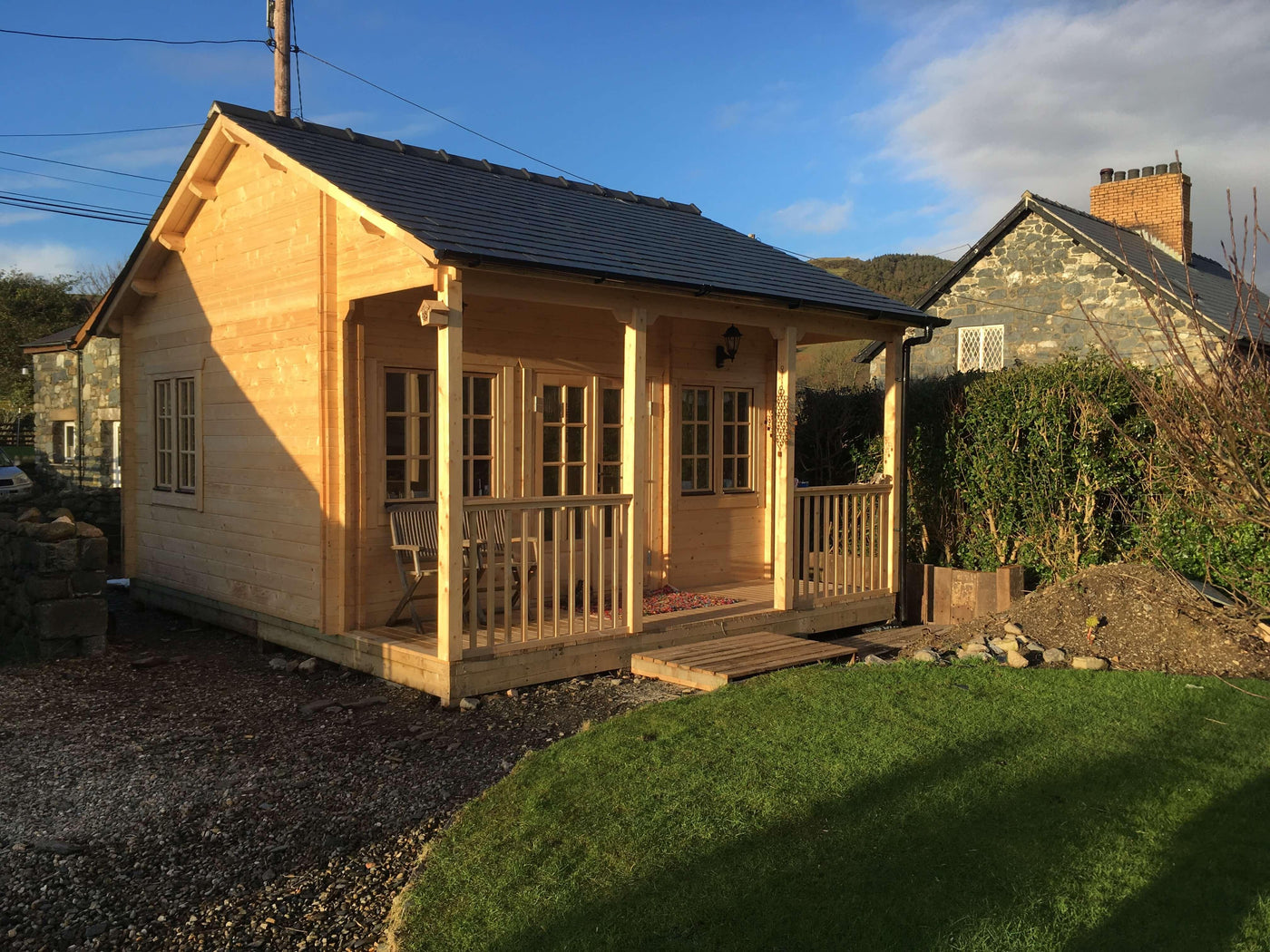 Charming wooden granny annexe with porch in sunny garden setting.