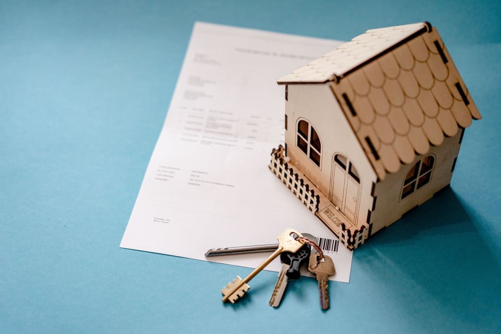Model house with keys on legal rental agreement documents.