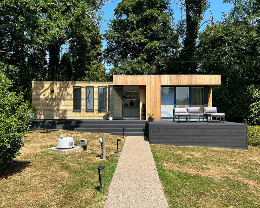 Modern granny annexe with deck in lush garden setting.