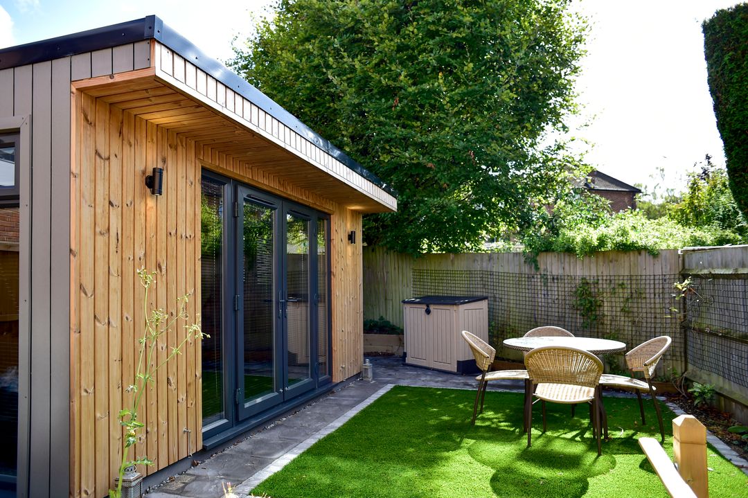 Modern granny annexe with wooden siding and garden seating area.