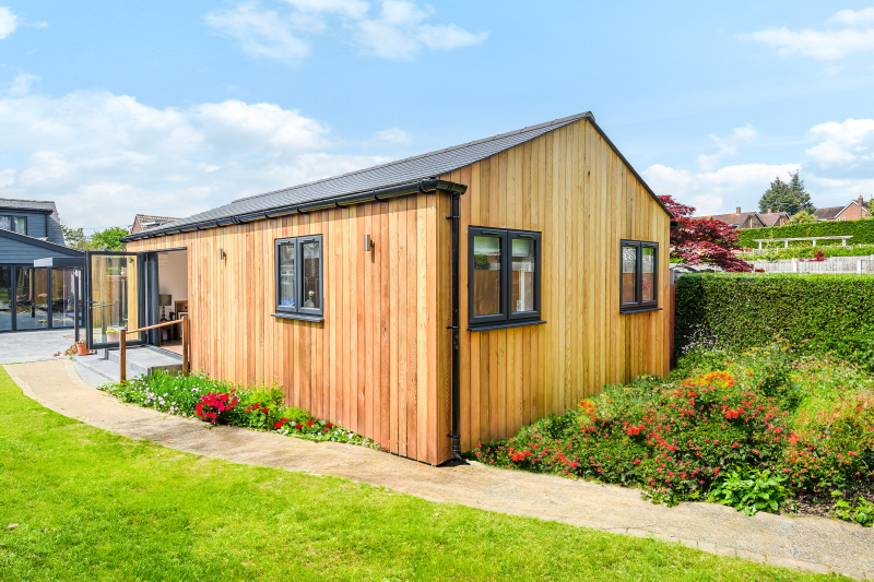 Wooden granny annexe surrounded by lush garden, ideal for renting.